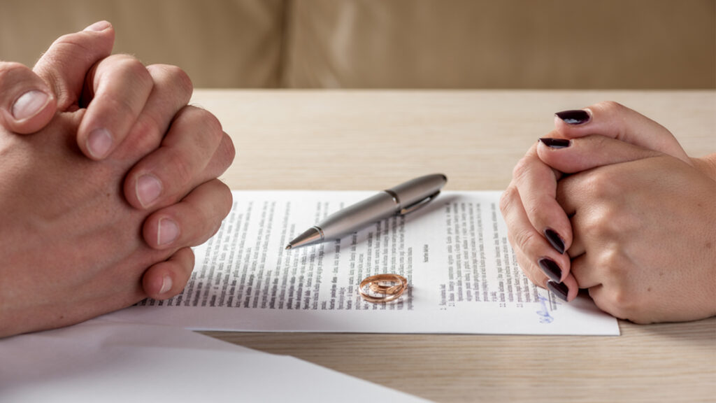 Refus de divorce : Mains croisées d’un couple face à un document de divorce.