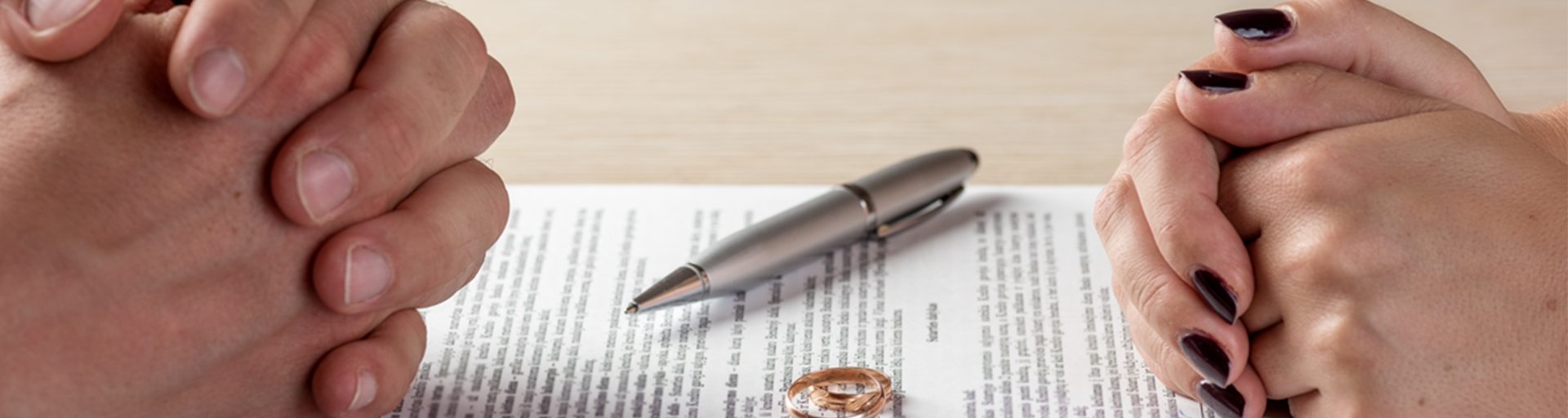 Refus de divorce : Mains croisées d’un couple face à un document de divorce.