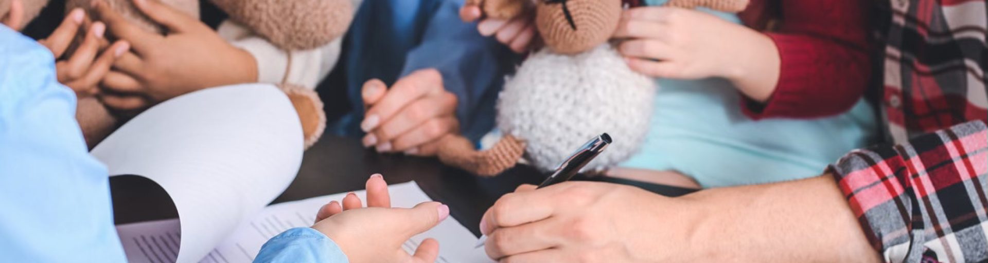 Signature d’un document d’adoption simple ou plénière en présence d’enfants et de peluches.